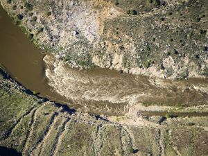 Aerial of Maybell Ditch with muddy water flowing through arid banks. 