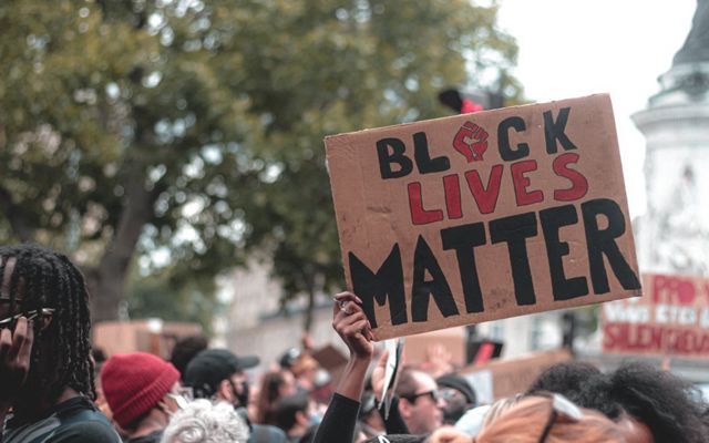 A sign reading Black Lives Matter is held aloft over a group of protestors.