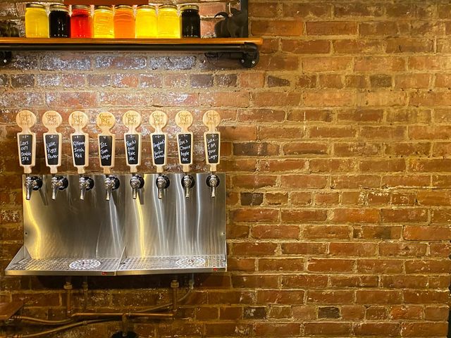 A row of 8 metal taps hang on a brick wall at The Copper Pig Brewery in Lancaster, New Hampshire.