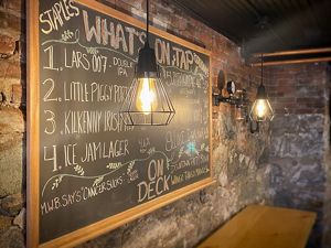 A chalkboard on a brick wall outlines what's on tap at the Copper Pig Brewery. 