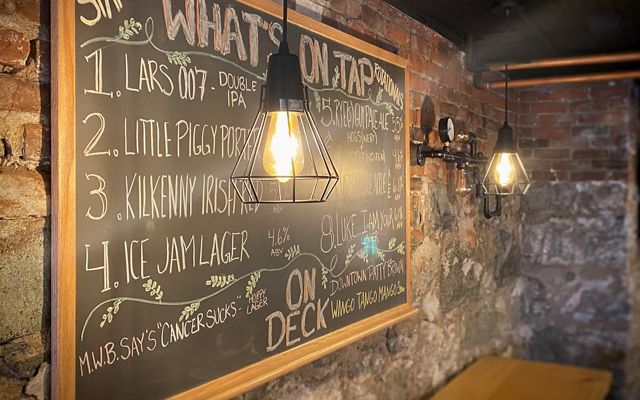 A chalkboard on a brick wall outlines what's on tap at the Copper Pig Brewery. 