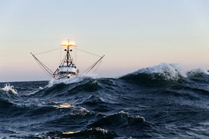 A boat pictured on the very choppy waters of the open ocean.