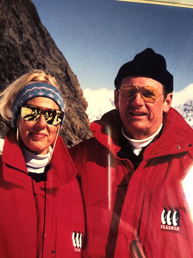 Art and Corinne Smith, both wearing red winter coats, pose together for a photo.