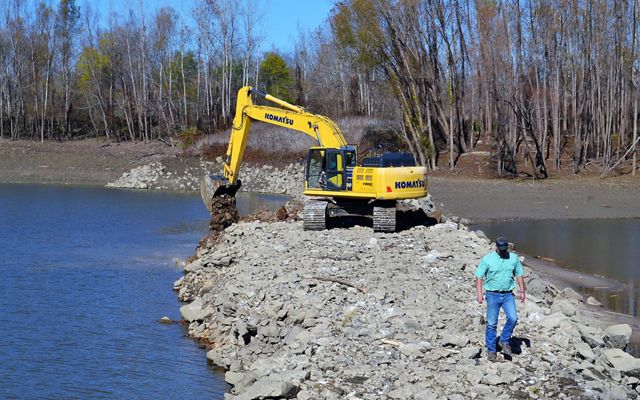 A backhoe digs a notch into a dike at Coffee Point