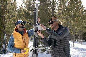 Two people use scientific instruments to measure snow.