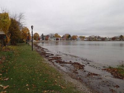 Water covers a path along a shoreline with autumnal trees on one side and water on the other.