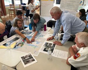 A group of people gather around a table to look at a map.