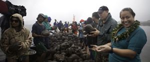 A group of people rebuilding a fishpond wall with stones.