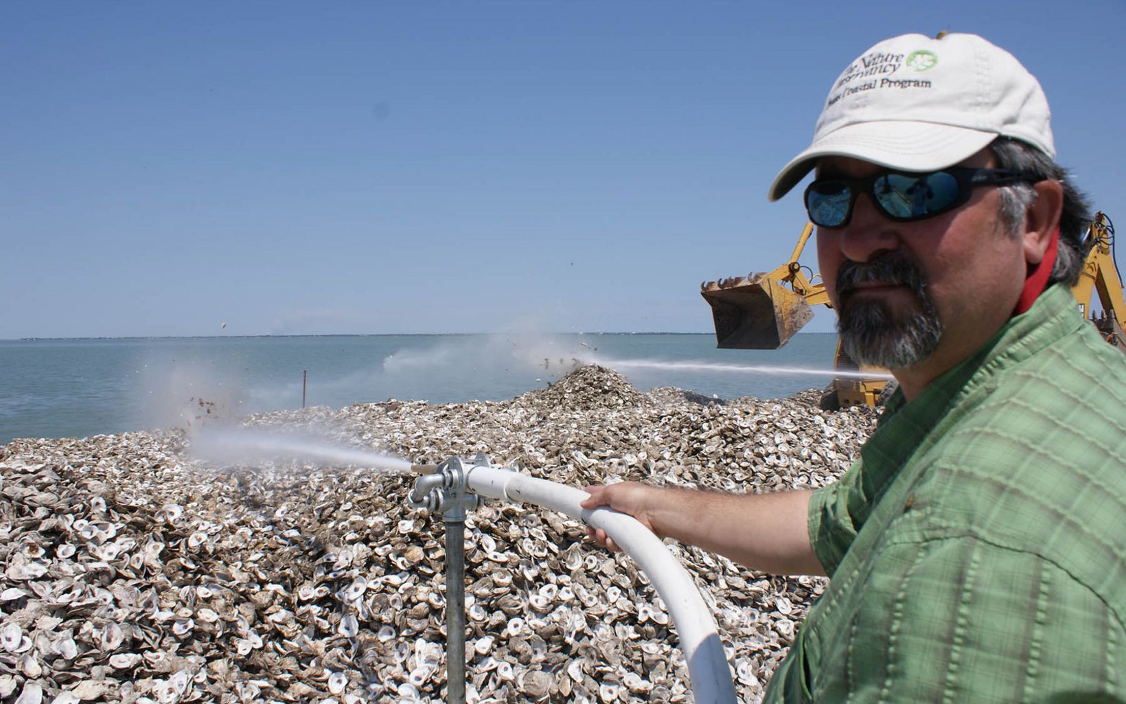 TNC upper Gulf Coast program manager Mark Dumesnil blows oyster shells into Copano Bay with a fire hose to restore oyster reefs for oysters and fish. 