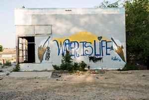 Graffiti reading 'water is life' on an abandoned building.