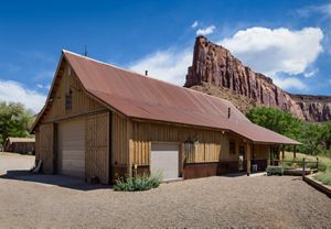 A barn at the Canyonlands Research Center, with a large red rock formation in the background.