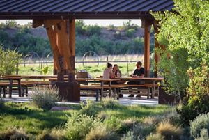 Three people sit at a picnic table under an awning at the pavilion at the Canyonlands Research Center.