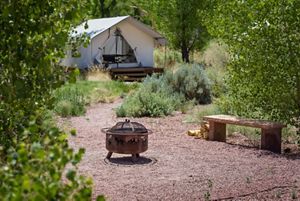 A tent and camp area at the Canyonlands Research Center, with a fire pit and bench in a dirt clearing.