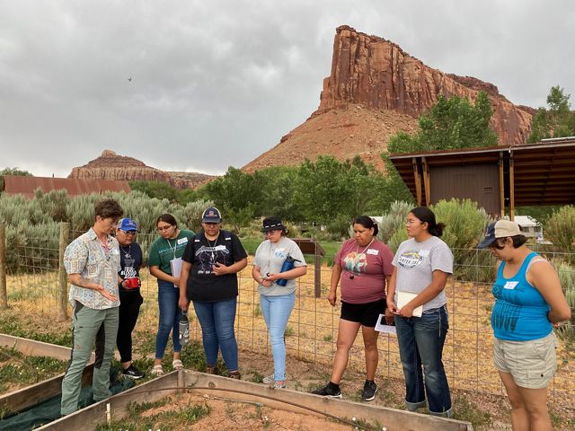 A group of interns standing over a biocrust garden at the Canyonlands Research Center in Utah.