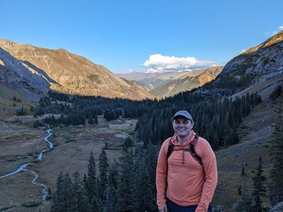 A picture of Kyle Sanduski standing in front of mountains.