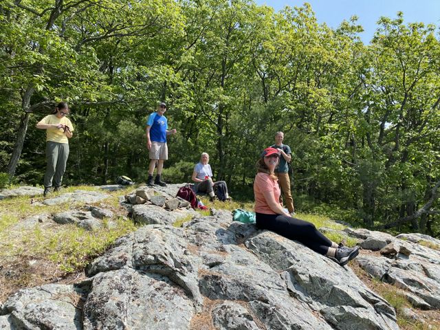 A group of people sitting on a rock in nature.