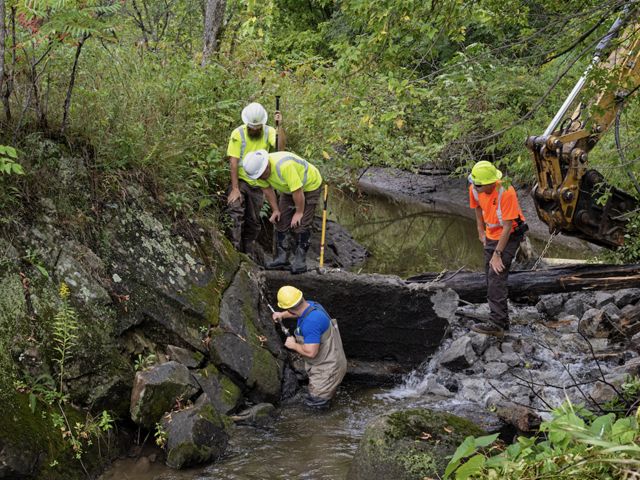 Three people removing a dam.