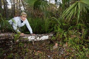 mujer joven avanza lentamente a cuatro patas sobre tronco, frente a la cámara