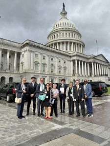 A group of people stand in front of the U.S. Capitol Building.