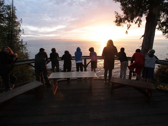 behind view of young people looking from a deck out towards a sunset