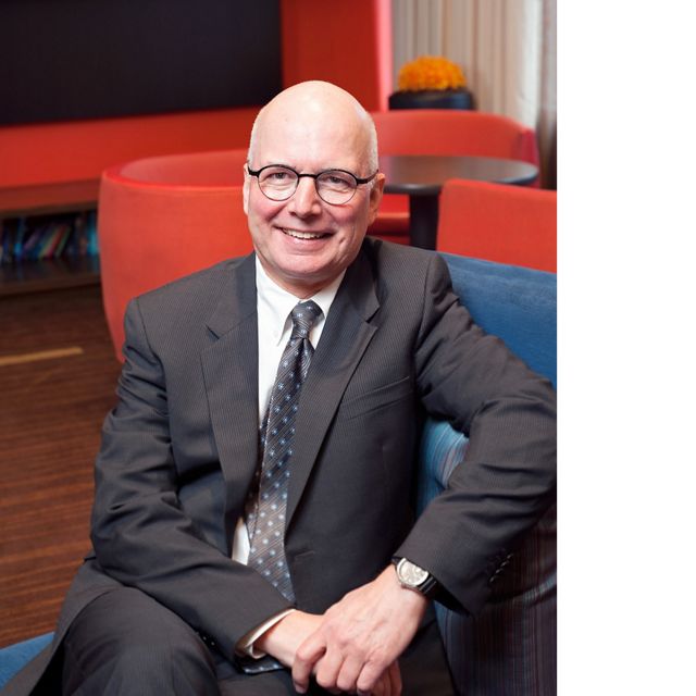 headshot of a white bald man sitting in a suit