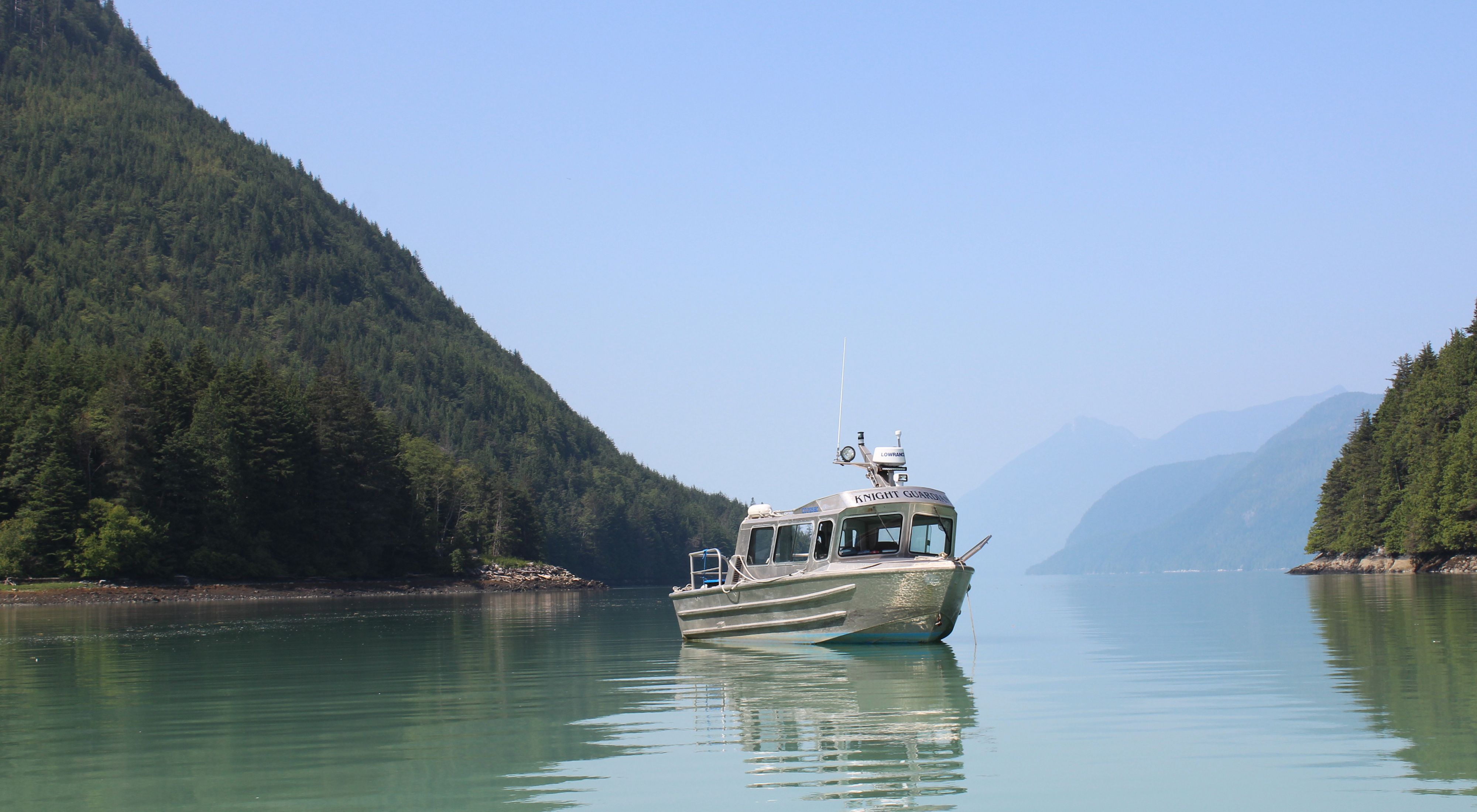 a boat on blue water with mountains in the background