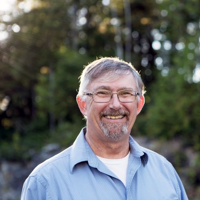 outdoor headshot of a smiling white man wearing glasses