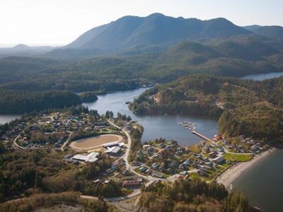 Aerial view of small island village surrounded by tree-covered mountains.
