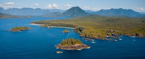 Aerial view of waters in Clayoquot Sound on the coast of British Columbia, with forest-covered mountains in the background.