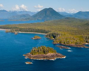 Aerial view of waters in Clayoquot Sound on the coast of British Columbia, with forest-covered mountains in the background.