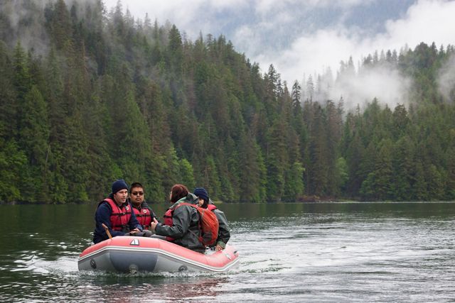 Photo of four people in a Zodiac-style boar on a river in the Great Bear Rainforest.