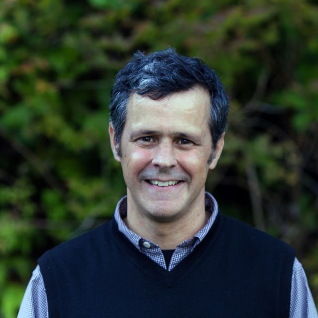 outdoor headshot of a smiling man with dark hair