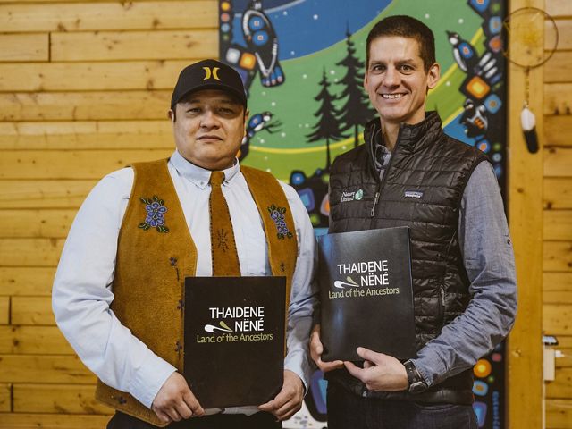 Łutsël K’e Dene First Nation Chief Marlowe stands with Nature United Executive Director Hadley Archer holding signed agreements that helped establish the Land of the Ancestors