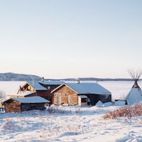 a few small buildings and a teepee covered in snow