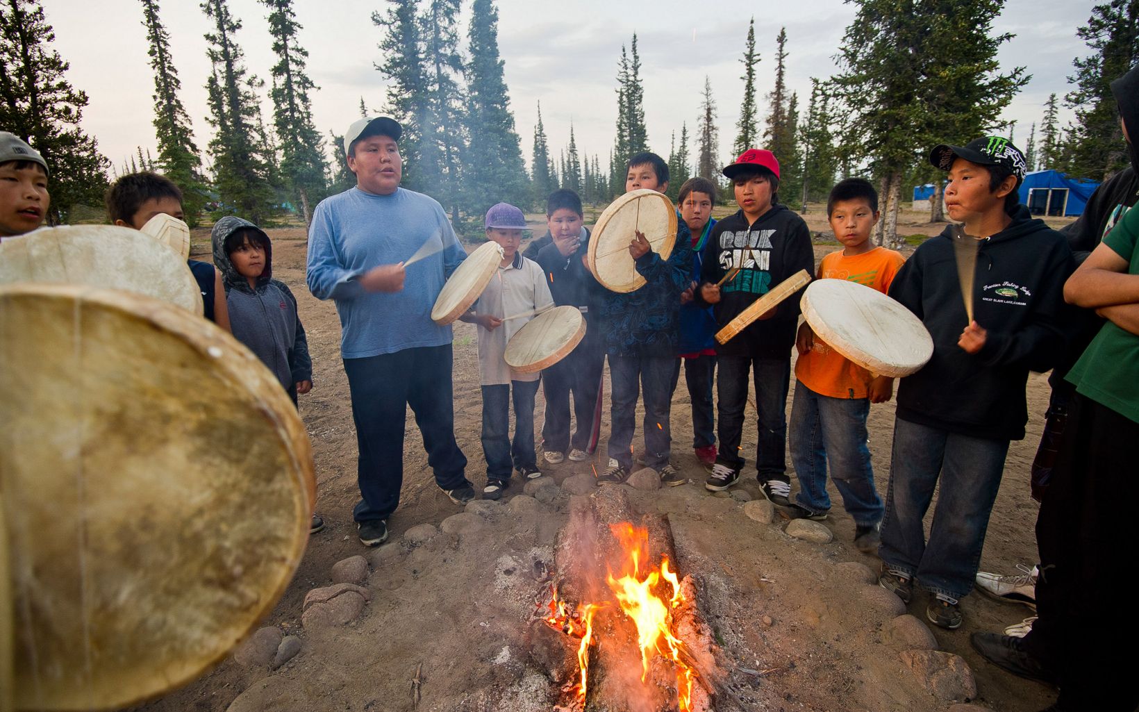 The Place Where God Began Dene First Nation youth beat drums around a fire during a spiritual gathering after returning from a canoe trip on the Upper Thelon River. © Ami Vitale