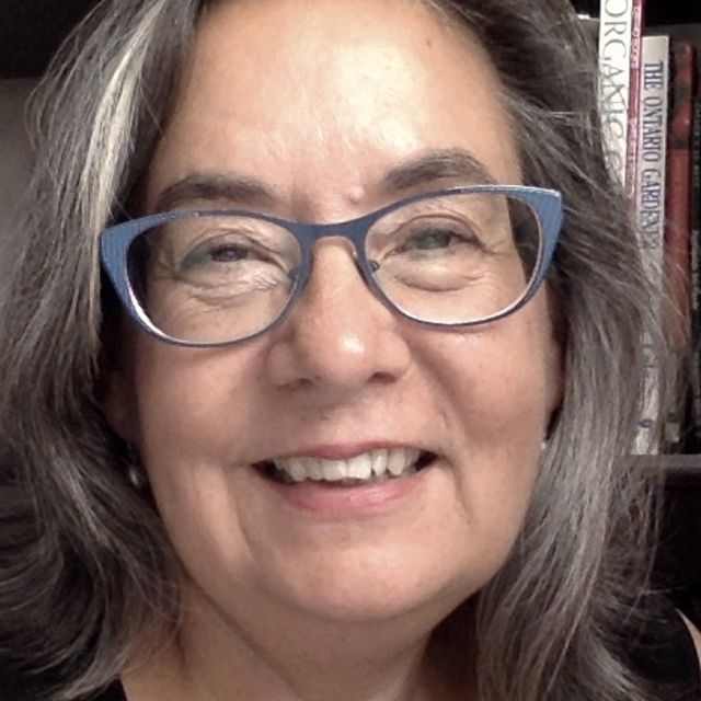 a woman with gray hair and glasses smiling