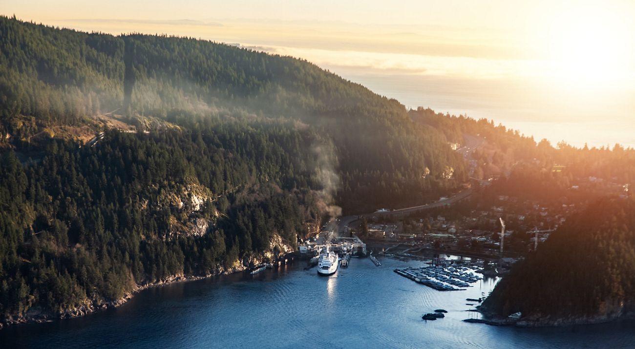 a ferry boat leaving a busy port on a tree-covered coast in Vancouver