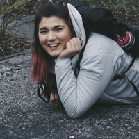 a woman leaning on a rock in front of a waterfall
