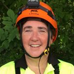 headshot of a woman in a yellow safety vest and an orange helmet