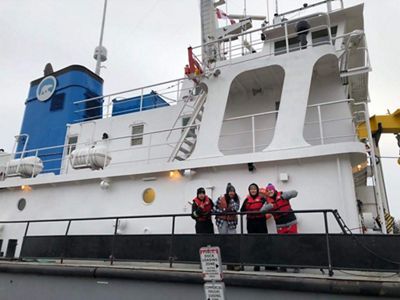 Young people from communities in the NWT, including Łutsël K’é, wave from aboard a research vessel setting sail on Tu Nedhé (also known as Great Slave Lake).