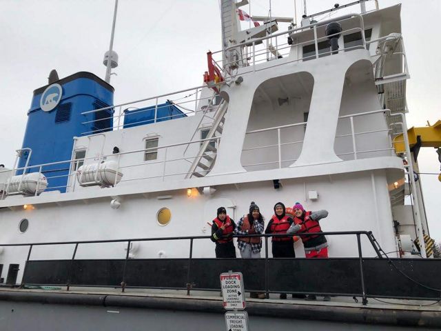 Young people from communities in the NWT, including Łutsël K’é, wave from aboard a research vessel setting sail on Tu Nedhé (also known as Great Slave Lake). 