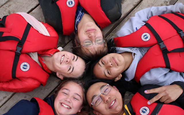Five smiling students who sailed with Northern Youth Leadership, Arctic Foundation and Nature United on a research voyage on Great Slave Lake in 2020.
