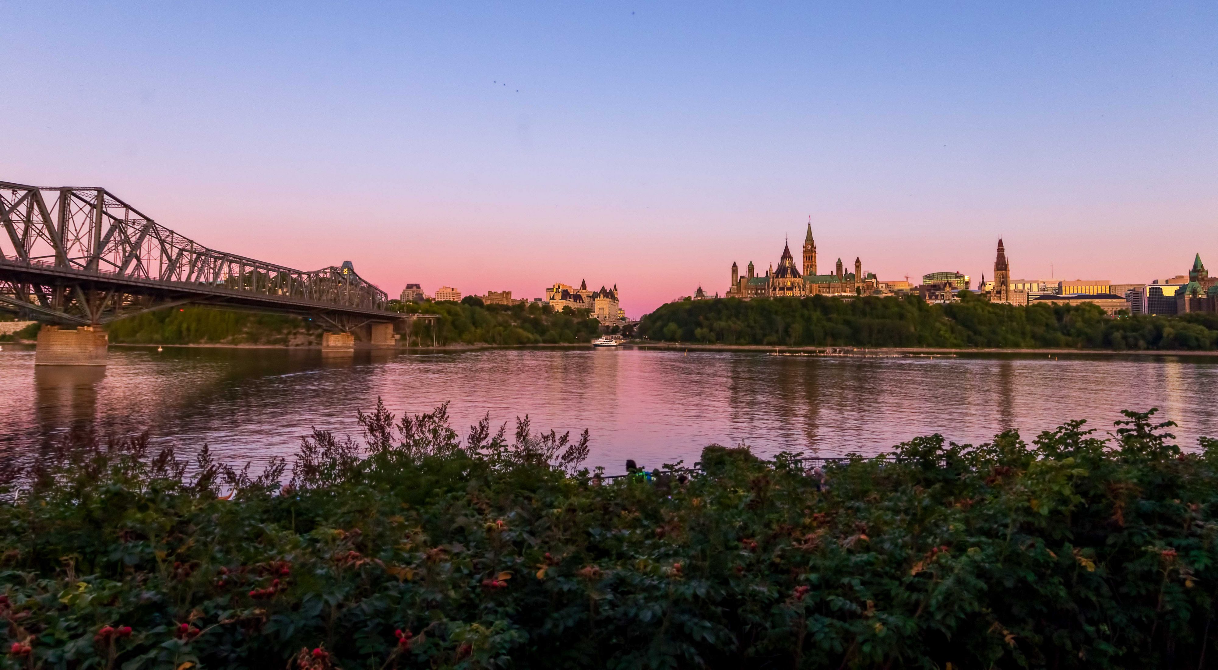 a river and a bridge in front of the canadian parliament building in ottawa 