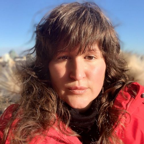 a headshot of a brown-haired woman in a red coat