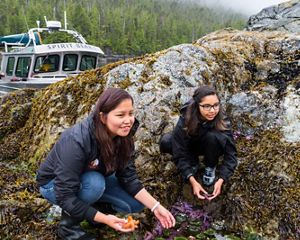 a group of four teens looking at small rocks