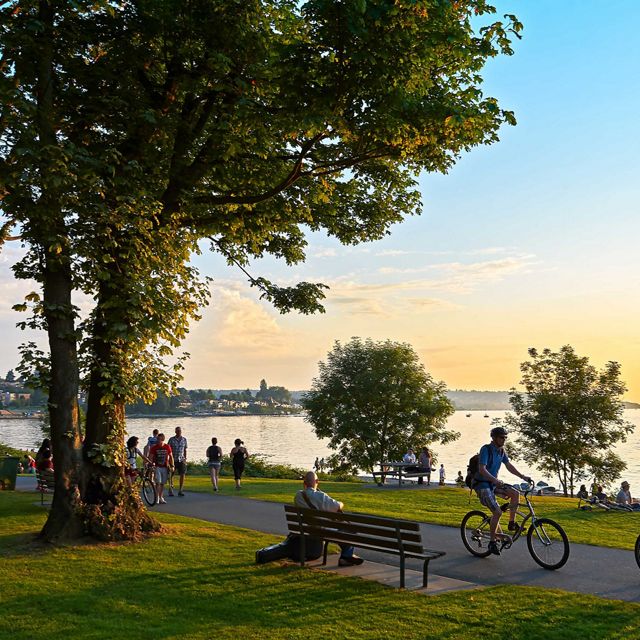 Young couple cycling, others walking or jogging late afternoon and enjoying the sunset at Stanley Park Vancouver, British Columbia, Canada