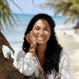 Jeamir Diaz smiles for a photo among the ocean and palm trees.