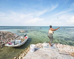 In West End, Grand Bahama, a woman fishes for snapper among conch middens.