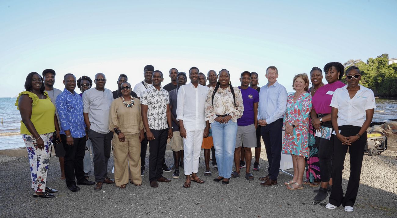 Group of people posing for a photo with the ocean in the background.