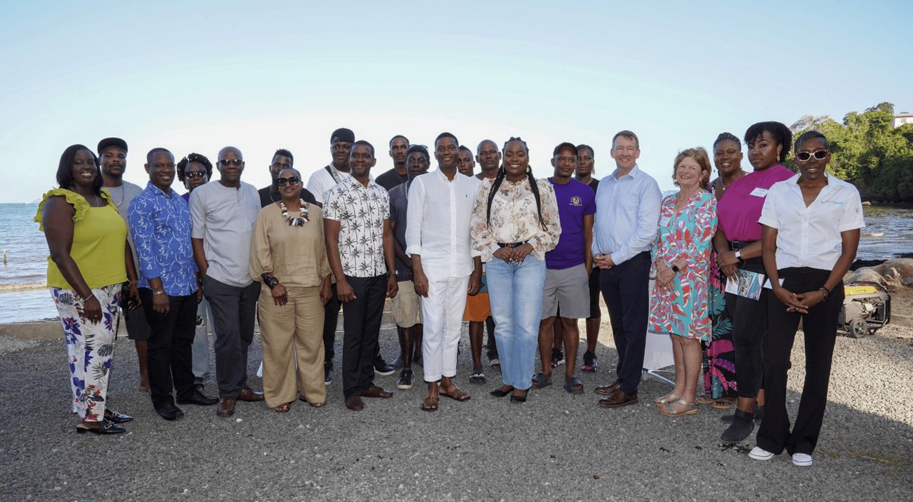 Group of people posing for a photo with the ocean in the background.